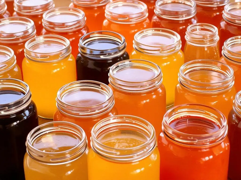 Array of honey jars with varying colors, from light golden to dark amber, representing different nectar sources and seasons, detailed close-up